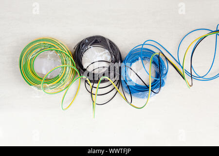 Elektrische Kabel Spule in drei Farben blau und grün gelb Schwarzerde Boden Stockfoto