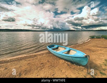 Lonely Fischereifahrzeug Boot am Strand an der ruhigen See. Laminat- oder Fischerboot in einen stillen See Wasser Stockfoto