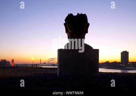 Skulptur Echo des Poseidon bei Sonnenuntergang, Skulptur Rhineorange im Hintergrund, Duisburg, Deutschland Stockfoto