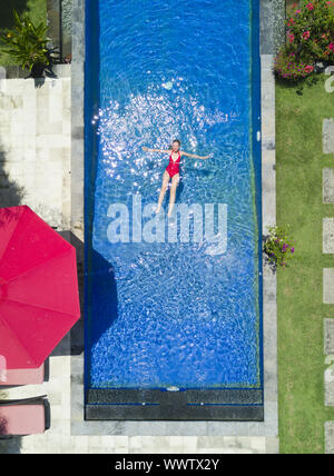 Die junge schöne Frau, schwimmt im Pool in einem tropischen Garten. Stockfoto