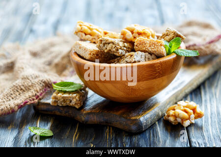 Honig bars mit Erdnüsse, Sesam und Sonnenblumenkerne in eine hölzerne Schüssel. Stockfoto