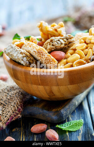 Honig bars mit Erdnüsse, Sesam und Sonnenblumenkerne in eine hölzerne Schüssel Nahaufnahme. Stockfoto