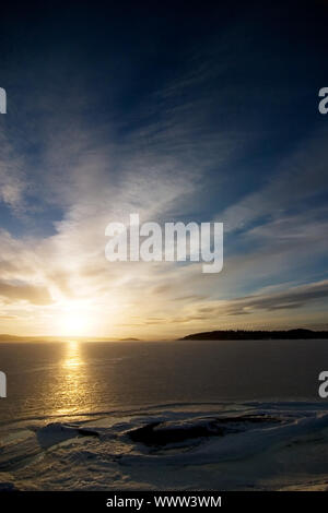 Einen goldenen Sonnenuntergang hinunter hinter einem Hügel über einen gefrorenen See-Fjord. Oslo Fjord im März. Stockfoto