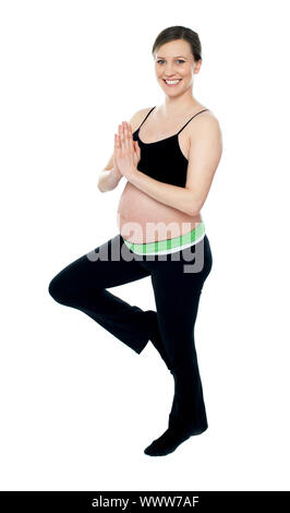 Porträt der schönen schwangeren Yoga zu tun. Stehen auf einem Bein vor weißem Hintergrund isoliert Stockfoto