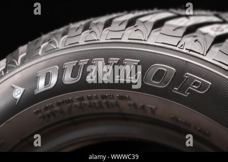 Der Dunlop Logo ist groß auf einem schwarzen Hintergrund, auf der Seite der neuen Reifen. Stockfoto