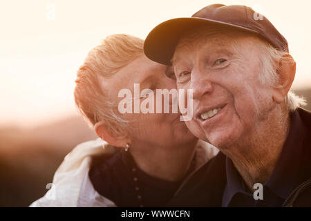 Glücklicher Mann von Frau außerhalb küsste bei Sonnenuntergang Stockfoto