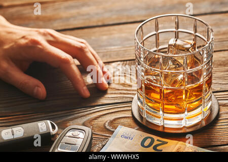 Die Hand des Mannes erreichen zu Glas mit Alkohol trinken und Auto-Taste. Trinken und Fahren. Stockfoto