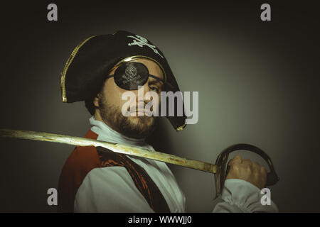 Mann mit Bart, gekleidet wie ein Pirat mit Augenklappe und Stahl Schwert Stockfoto