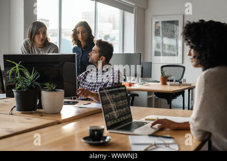 Vielfältige Gruppe von jungen Designern gemeinsam auf einem Computer Stockfoto