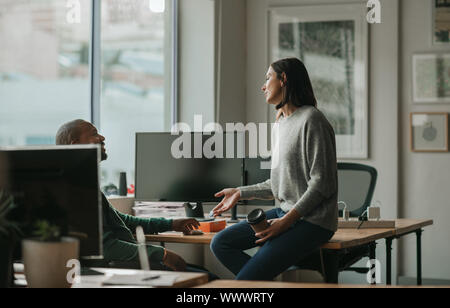 Designer im Gespräch mit einem männlichen Kollegen während einer Pause Stockfoto