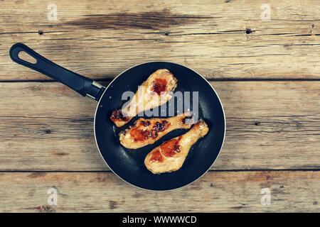 Hähnchen gegrillt Beine. Fried Chicken Beine in einer Pfanne auf einem Holztisch Stockfoto