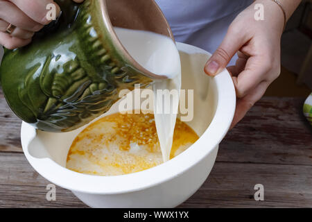 Das Kochen von Essen. Frau Koch gießt Milch in eine Schüssel geben. Backwaren. Stockfoto