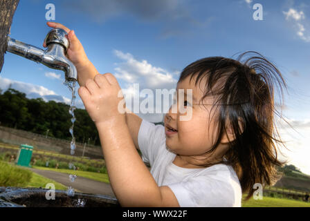 Süße asiatische Kinder waschen Hände im Park. Stockfoto