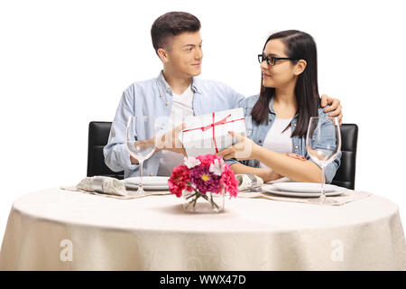 Junges Paar an einem Tisch im Restaurant Holding ein Geschenk auf weißem Hintergrund Cute Stockfoto