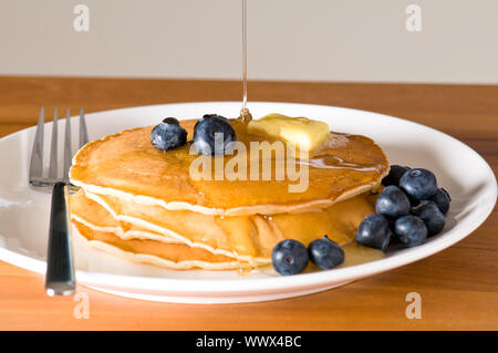Heidelbeer-Pfannkuchen auf einem Teller mit der Gabel auf einem Holztisch Stockfoto