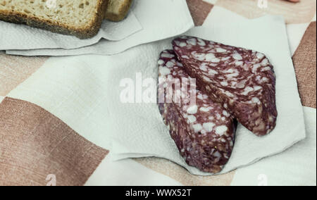 Zwei Scheiben Wurst und Brot auf der Serviette. Stockfoto