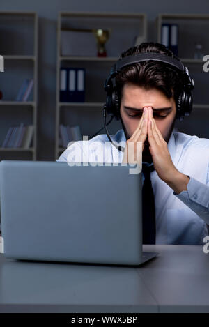 Junger Mann in Call Center Konzept arbeiten Ende Überstunden im Büro Stockfoto