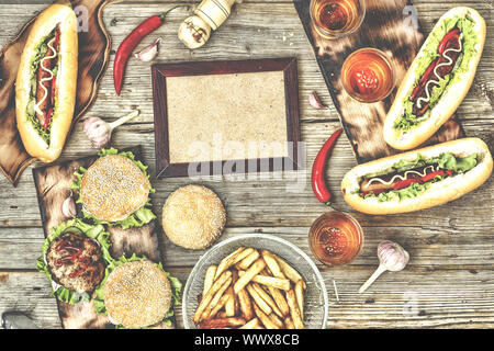 Ansicht von oben hausgemachte Burger mit Rindfleisch, Hot Dogs und Bier auf einer hölzernen Tisch. Im rustikalen Stil Stockfoto