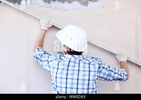 Arbeiter richtet Wand für die Leitung Stockfoto