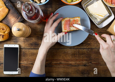 Frau, die ein Sandwich mit Lachs und Butter. Stockfoto