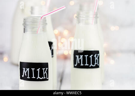 Glasflaschen von Milch mit Strohhalmen und antiken Milchflasche im Hintergrund. Geringe Schärfentiefe. Stockfoto