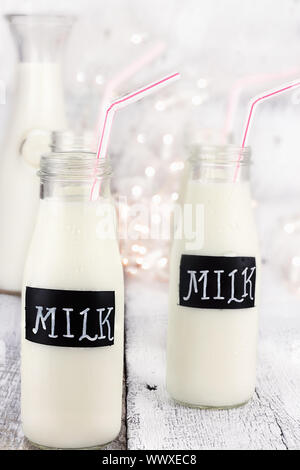 Glasflaschen von Milch mit Strohhalmen und antiken Milchflasche im Hintergrund. Geringe Schärfentiefe. Stockfoto