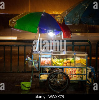Ein regnerischer Abend in Bangkok. Auch die Frucht hat der Verkäufer innerhalb ausführen Stockfoto