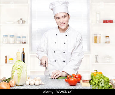 Junge Köchin schneiden Zwiebeln in Küche Stockfoto