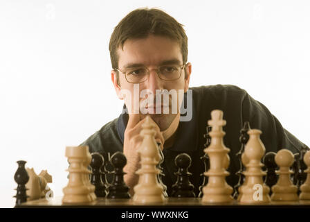 junger Mann spielt Schach gegen einen weißen Hintergrund isoliert Stockfoto