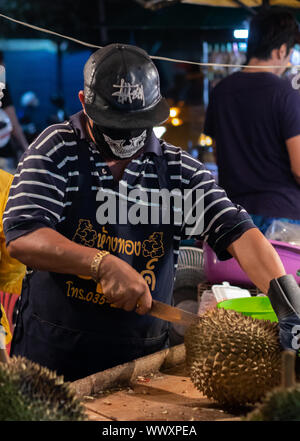 Ein Mann zerhackt Durian Frucht in einer Thailand Nacht Markt Stockfoto