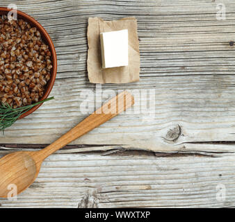 Buchweizen Porridge mit Butter in einem Ton Schüssel gegen einen hölzernen Hintergrund. Konzept: vegetarisches Essen, Stockfoto