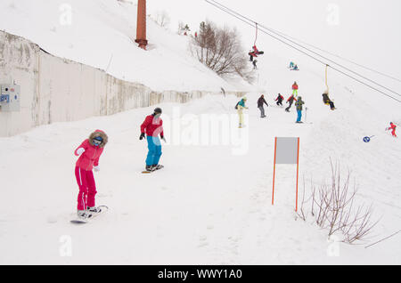 Dombay, Russland - 7. Februar 2015: Menschen fahren auf die verschneiten Pisten des Skigebietes Dombai Stockfoto