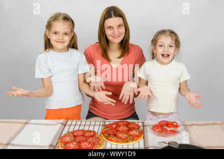 Mutter mit zwei kleinen Töchtern gerne zeigen gemachte Pizza mit Tomaten Stockfoto