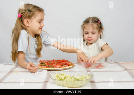 Zwei kleine Mädchen am Tisch verteilt auf Tomaten pizza Stockfoto