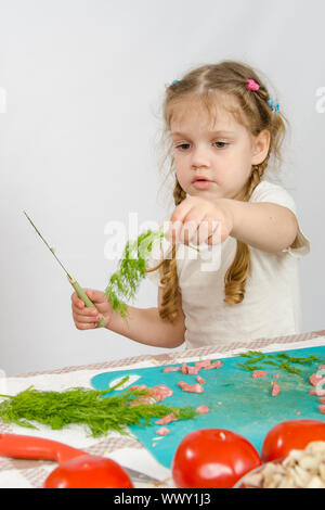 Sechs Jahres altes Mädchen Blick auf Bund Petersilie ist in seiner Hand hält. Stockfoto