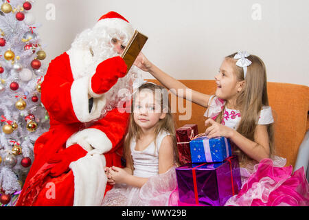 Santa Claus verleiht Geschenke ein Mädchen, die anderen sitzen im Wartezimmer Stockfoto