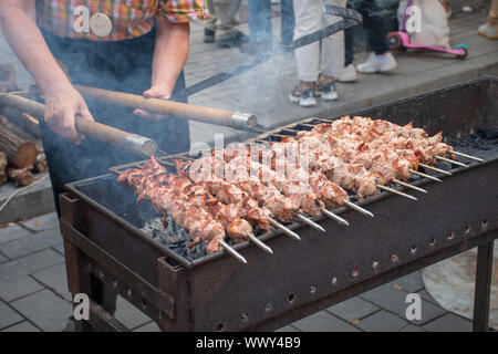 Nahaufnahme von Fleischspieße, Gegrilltes in einem Grill, schaschlik oder shashlyk von Schweinefleisch für ein Pic Nic, Mann vorbereiten und Braten mit Mistgabeln Stockfoto