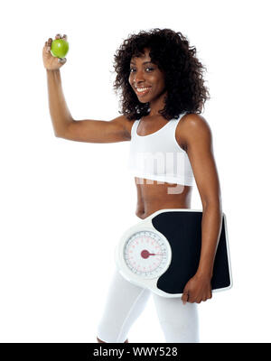 Athlet hält grünen Apfel und einem Gewicht von Maschine tragen weiße Sport-outfit Stockfoto