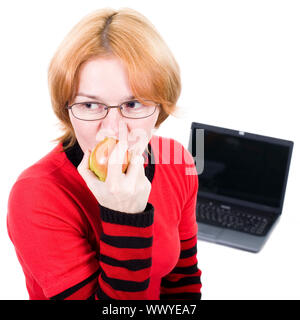 Die Frau in den Punkten beisst ein Apple gegen den Laptop Stockfoto