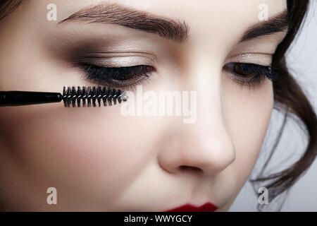 Close up Portrait von schöne junge brünette Frau Gesicht. Weibliche Anwendung Mascara auf die Wimpern Stockfoto