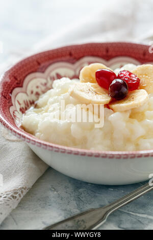 Schüssel mit Milch Reisbrei, Bananen, Beeren und Honig. Stockfoto