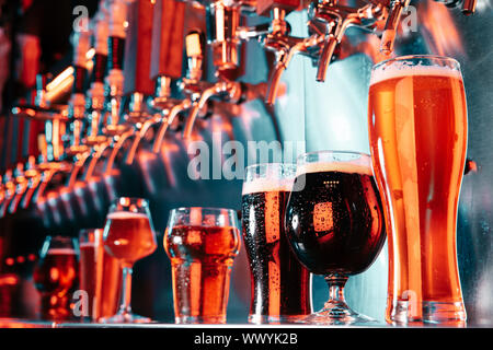 Gläser aus dunklen und hellen Bier, Pils, Lager, Stout, Porter in modernen und hellen Neonlicht mit Gießmaschine für den Hintergrund. Konzept der Urlaub, Spaß, Konferenz, Oktoberfest, grosse Freunde" Partei. Stockfoto