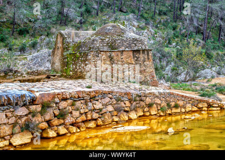 Alte Wassermühle auf dem bunten Fluss Odiel mit Pinienwald in Huelva, Andalusien, Spanien. Stockfoto