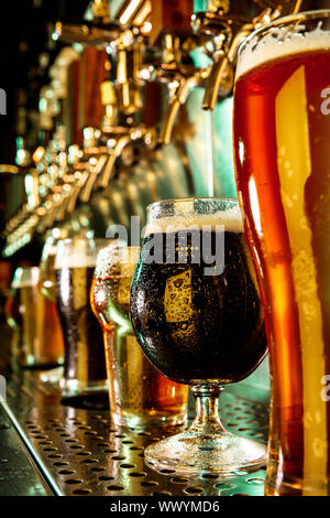 Gläser aus dunklen und hellen Bier, Pils, Lager, Stout, Porter in modernen und hellen Neonlicht mit Gießmaschine für den Hintergrund. Konzept der Urlaub, Spaß, Konferenz, Oktoberfest, grosse Freunde" Partei. Stockfoto