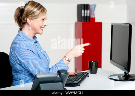 Geschäftsfrau zeigt am Computerbildschirm sitzen im Büro Stockfoto