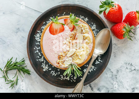 Gesunde rosa Smoothie Schüssel mit Erdbeeren, Bananen, Nüsse und Joghurt. Stockfoto