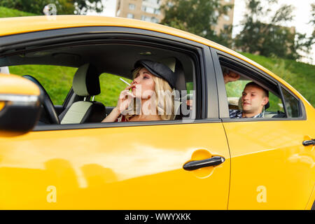 Bild des weiblichen Treiber mit Zigarette und männlichen Fahrgast im Taxi am Nachmittag Stockfoto