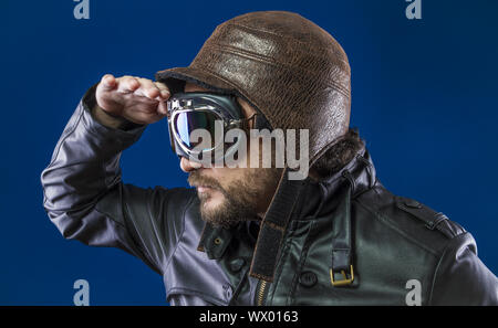 Pilot der 20s mit Sonnenbrille und Vintage aviator Helm. Trägt Lederjacke, Bart und ausdrucksvollen Gesichtern Stockfoto