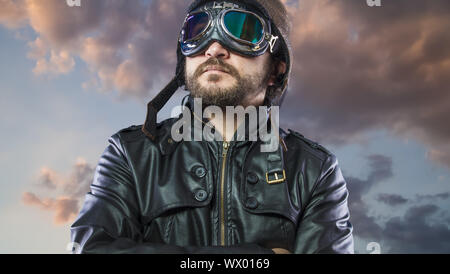 Stolz, Pilot der 20s mit Sonnenbrille und Vintage aviator Helm. Trägt Lederjacke, Bart und ausdrucksvollen Gesichtern Stockfoto