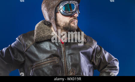 Pilot der 20s mit Sonnenbrille und Vintage aviator Helm. Trägt Lederjacke, Bart und ausdrucksvollen Gesichtern Stockfoto